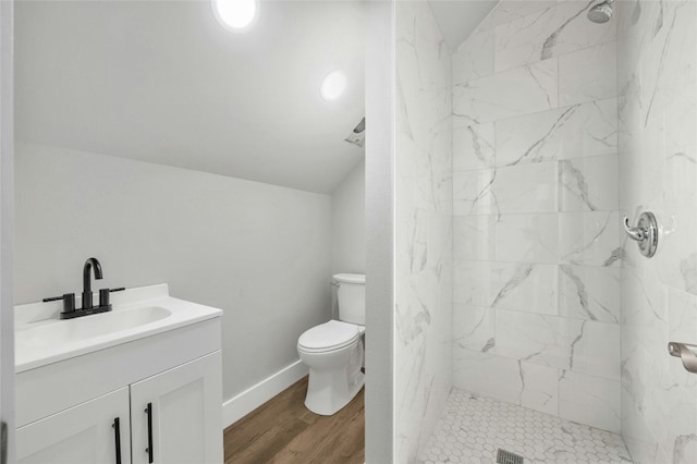 bathroom featuring toilet, vanity, lofted ceiling, and tiled shower