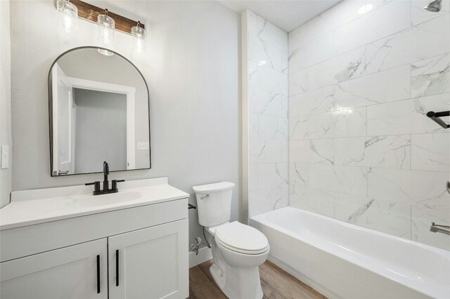 full bathroom with hardwood / wood-style floors, tiled shower / bath combo, toilet, and vanity