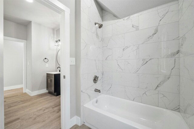 bathroom with hardwood / wood-style flooring, vanity, and tiled shower / bath combo