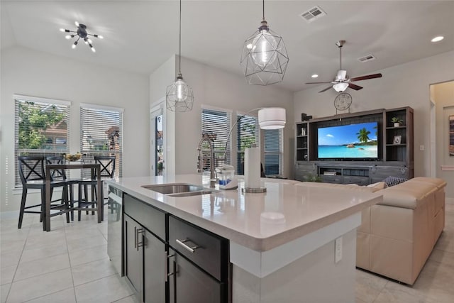 kitchen featuring a kitchen island with sink, sink, light tile patterned floors, dishwasher, and hanging light fixtures