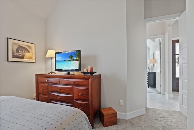 bedroom with ensuite bathroom, light colored carpet, and lofted ceiling