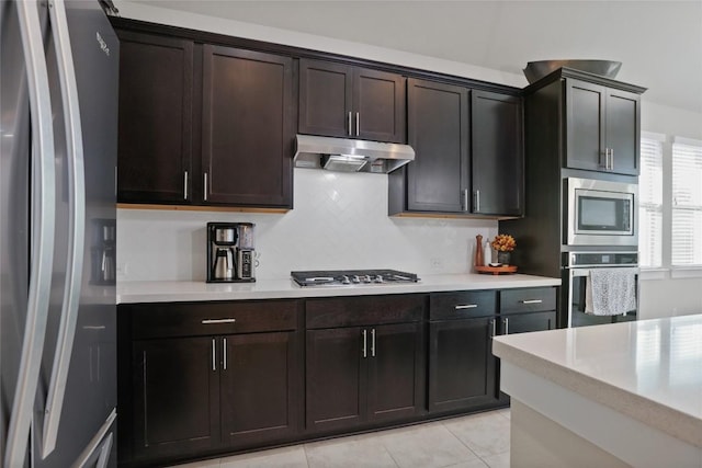 kitchen featuring appliances with stainless steel finishes, dark brown cabinetry, tasteful backsplash, and light tile patterned floors