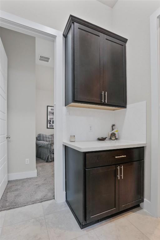 bar featuring light tile patterned flooring and dark brown cabinetry