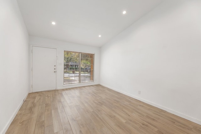 unfurnished room featuring light hardwood / wood-style floors and lofted ceiling