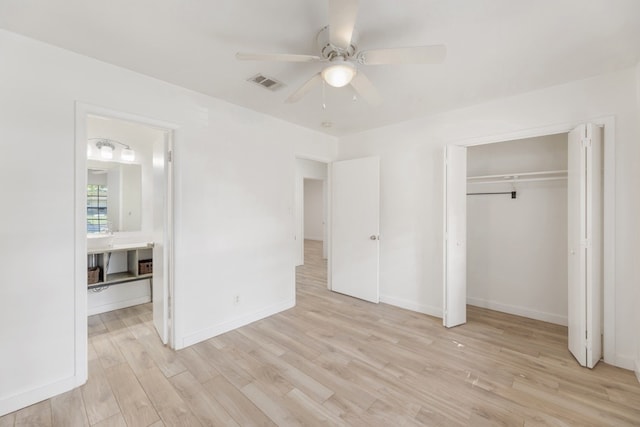 unfurnished bedroom with ceiling fan, light wood-type flooring, ensuite bathroom, and a closet