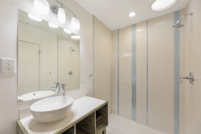 bathroom featuring a tile shower and vanity