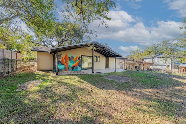 rear view of house featuring a lawn and a patio