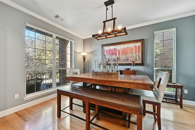 dining area with a chandelier, light hardwood / wood-style floors, and ornamental molding