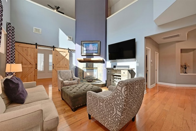 living room with a high ceiling, a barn door, and light hardwood / wood-style flooring