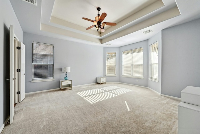 interior space with ceiling fan, a raised ceiling, and light colored carpet