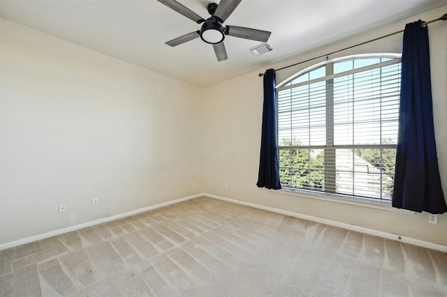 empty room with ceiling fan, light colored carpet, and a healthy amount of sunlight