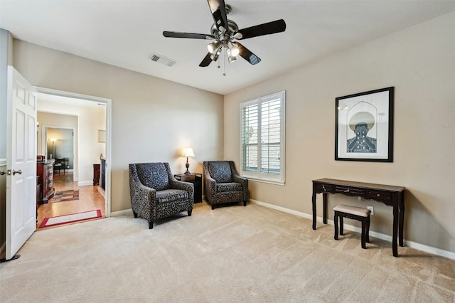 living area with ceiling fan and light colored carpet