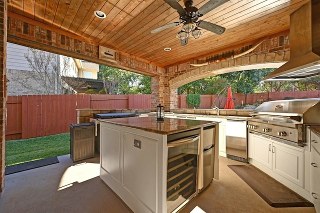 view of patio featuring ceiling fan, beverage cooler, exterior kitchen, a grill, and an outdoor wet bar