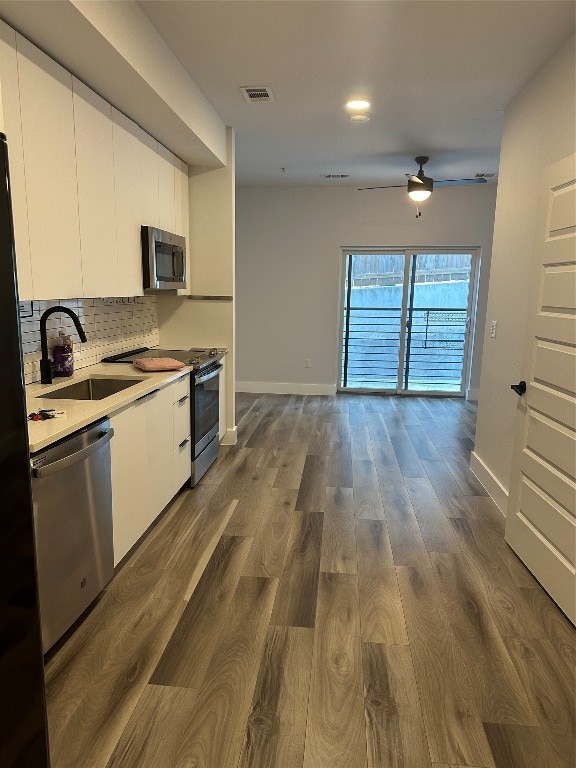 kitchen with backsplash, stainless steel appliances, sink, white cabinets, and dark hardwood / wood-style floors