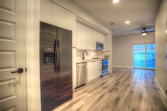 kitchen featuring white cabinetry, ceiling fan, light hardwood / wood-style floors, decorative backsplash, and appliances with stainless steel finishes