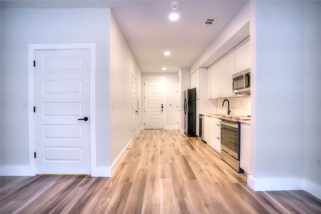 hallway with light hardwood / wood-style floors and sink