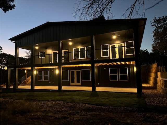 rear view of property with board and batten siding, french doors, a patio, and stairway