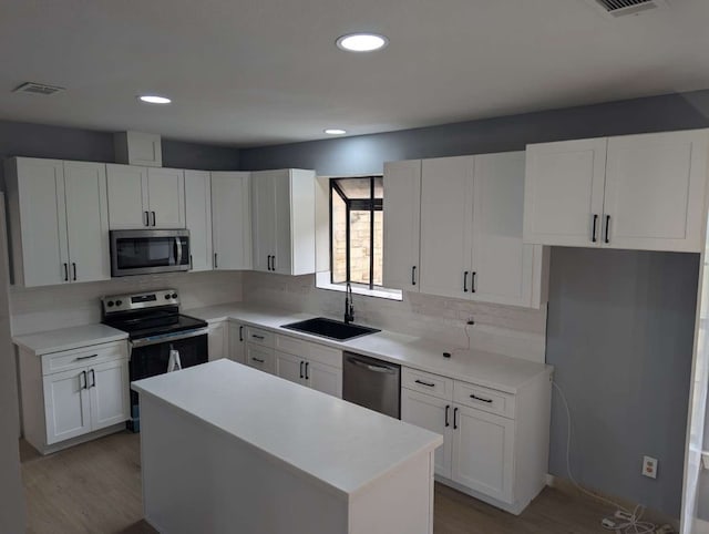 kitchen featuring decorative backsplash, a center island, white cabinetry, and stainless steel appliances