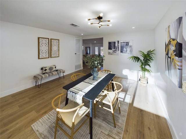 dining area with wood-type flooring and a chandelier