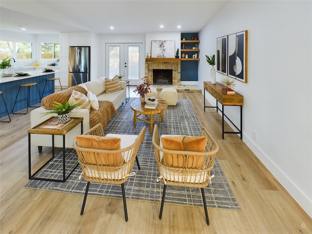 living room with a fireplace, french doors, a healthy amount of sunlight, and light hardwood / wood-style floors