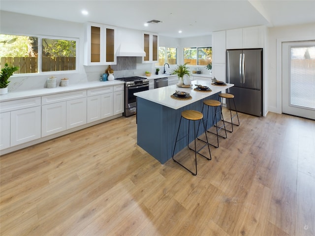 kitchen featuring appliances with stainless steel finishes, a kitchen breakfast bar, white cabinets, a center island, and light hardwood / wood-style floors