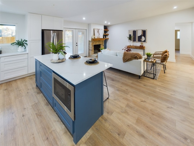 kitchen featuring a kitchen island, white cabinets, stainless steel appliances, and light wood-type flooring