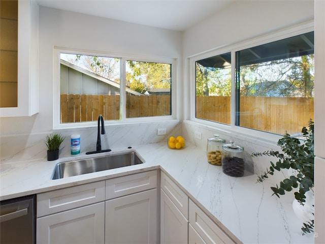 kitchen featuring dishwasher, white cabinetry, sink, and a wealth of natural light