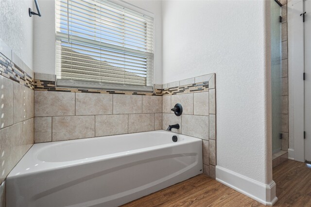 bathroom with a washtub and wood-type flooring