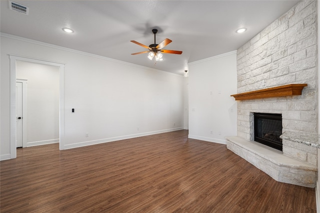 unfurnished living room featuring ceiling fan, a stone fireplace, ornamental molding, and dark wood-type flooring