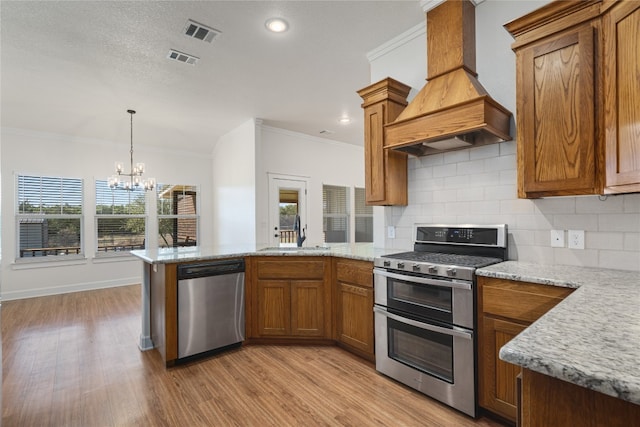 kitchen with premium range hood, sink, light hardwood / wood-style flooring, appliances with stainless steel finishes, and kitchen peninsula