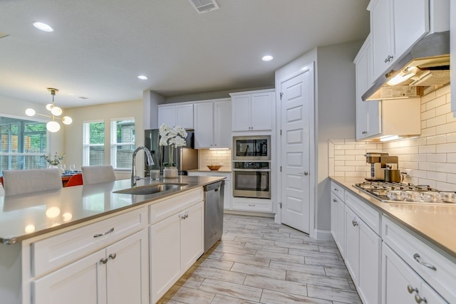 kitchen with backsplash, sink, white cabinets, and stainless steel appliances