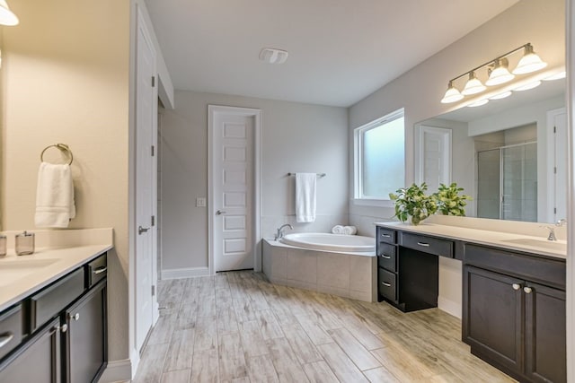 bathroom featuring plus walk in shower, wood-type flooring, and vanity