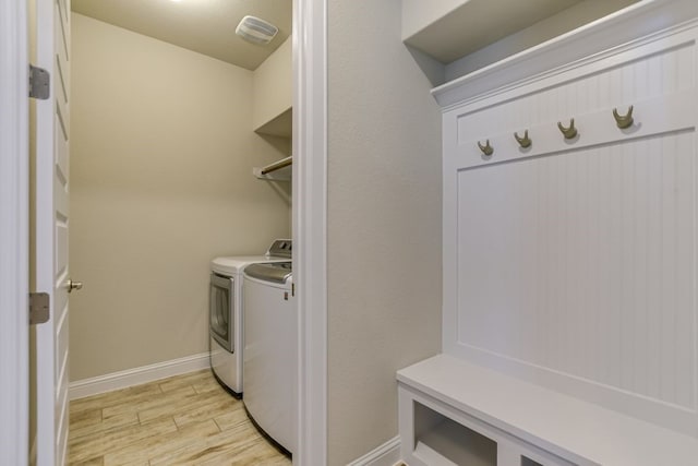 clothes washing area with washer and dryer and light hardwood / wood-style floors