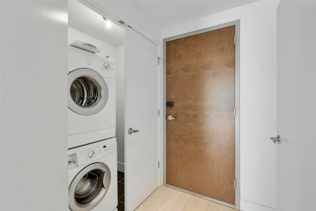 laundry room with light wood-type flooring and stacked washer / dryer