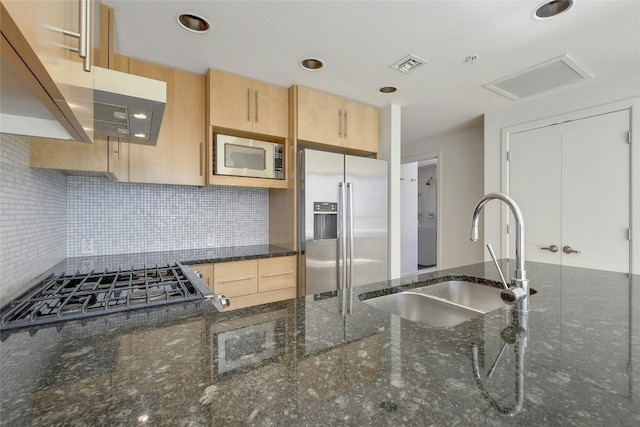 kitchen featuring light brown cabinets, sink, stainless steel appliances, and dark stone counters