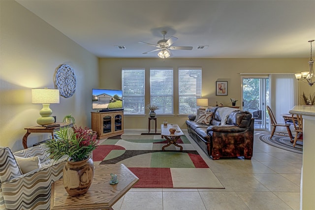 tiled living room featuring ceiling fan with notable chandelier