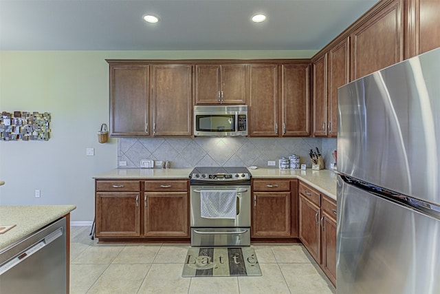 kitchen with light tile patterned floors, backsplash, and stainless steel appliances