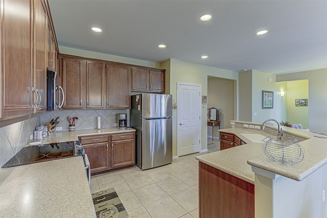 kitchen featuring sink, light tile patterned floors, an island with sink, tasteful backsplash, and stainless steel appliances