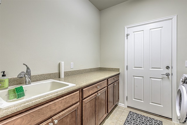 laundry room with sink, light tile patterned floors, cabinets, and washer / dryer