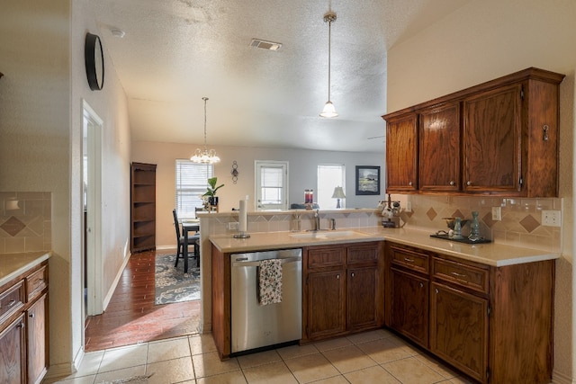 kitchen featuring stainless steel dishwasher, light hardwood / wood-style floors, decorative light fixtures, a textured ceiling, and decorative backsplash