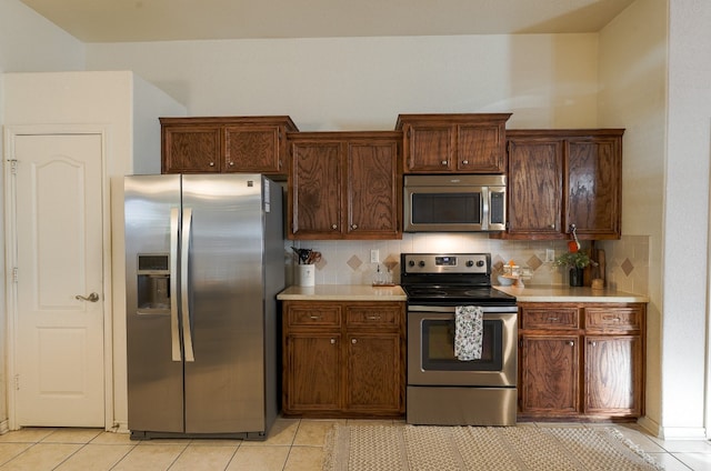 kitchen with decorative backsplash, appliances with stainless steel finishes, and light tile patterned floors