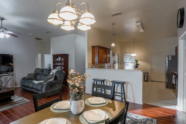 dining area featuring hardwood / wood-style floors, ceiling fan with notable chandelier, and a textured ceiling