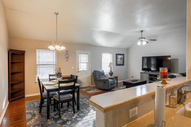 dining room featuring sink, dark hardwood / wood-style floors, a textured ceiling, vaulted ceiling, and ceiling fan with notable chandelier