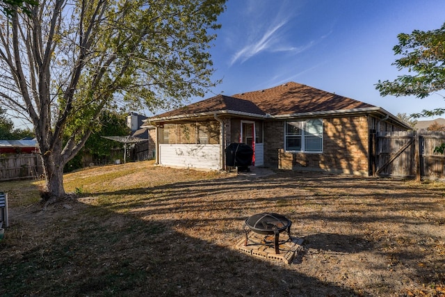 back of house featuring a fire pit and a lawn