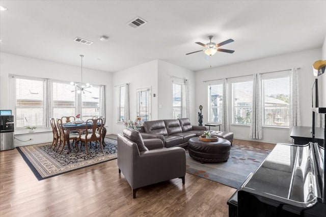 living room featuring plenty of natural light, dark wood-type flooring, and ceiling fan with notable chandelier