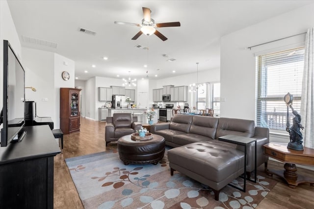 living room featuring ceiling fan with notable chandelier and dark hardwood / wood-style flooring