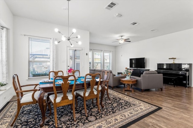 dining area with wood-type flooring, ceiling fan with notable chandelier, and a wealth of natural light