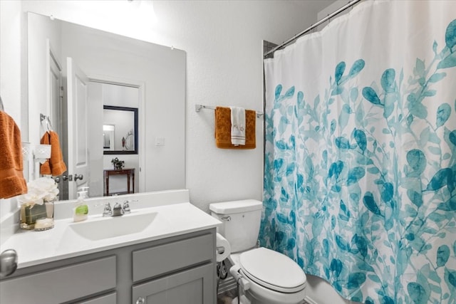 bathroom with curtained shower, vanity, and toilet