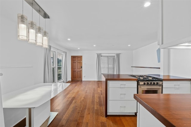 kitchen with gas range, white cabinetry, decorative light fixtures, and hardwood / wood-style flooring