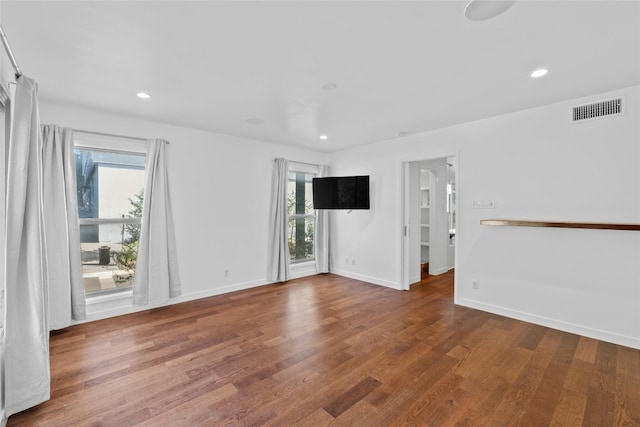 empty room with dark hardwood / wood-style flooring and a healthy amount of sunlight